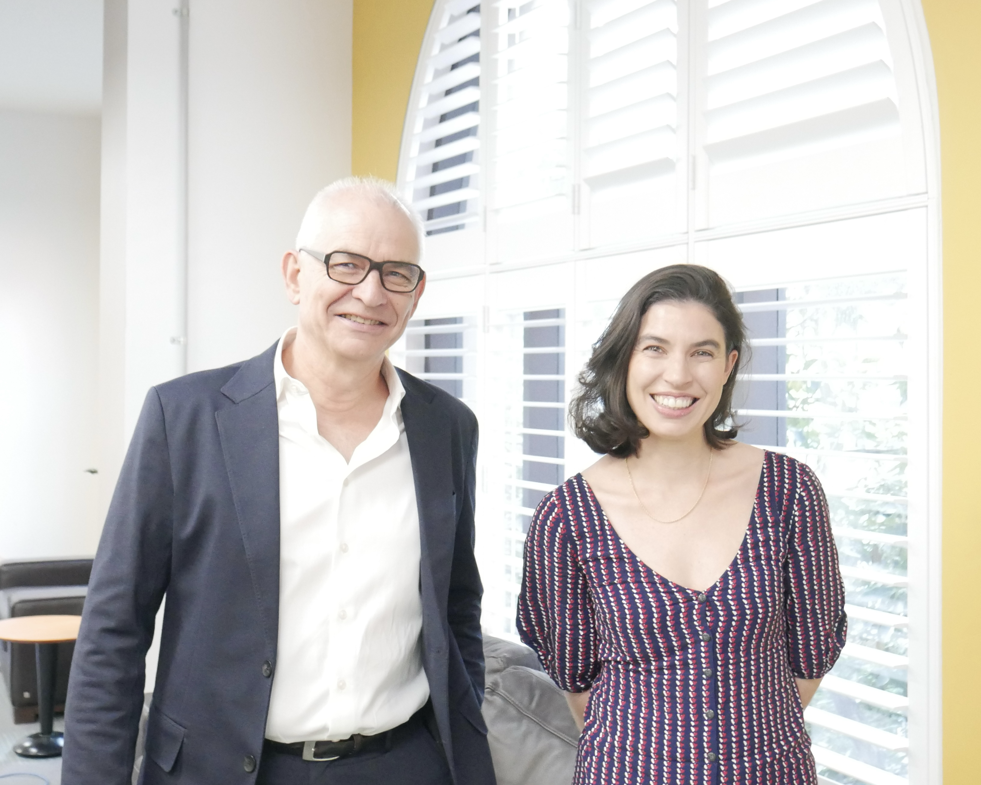 Photo of a smiling man and woman in an office, Michael Gordon-Smith alongside his successor Patrizia Di Biase-Dyson